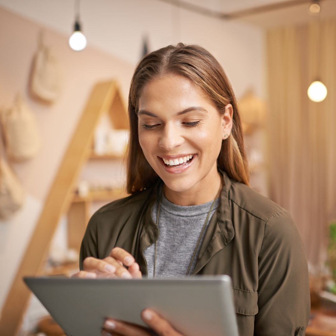 Woman smiling while looking at a tablet. 