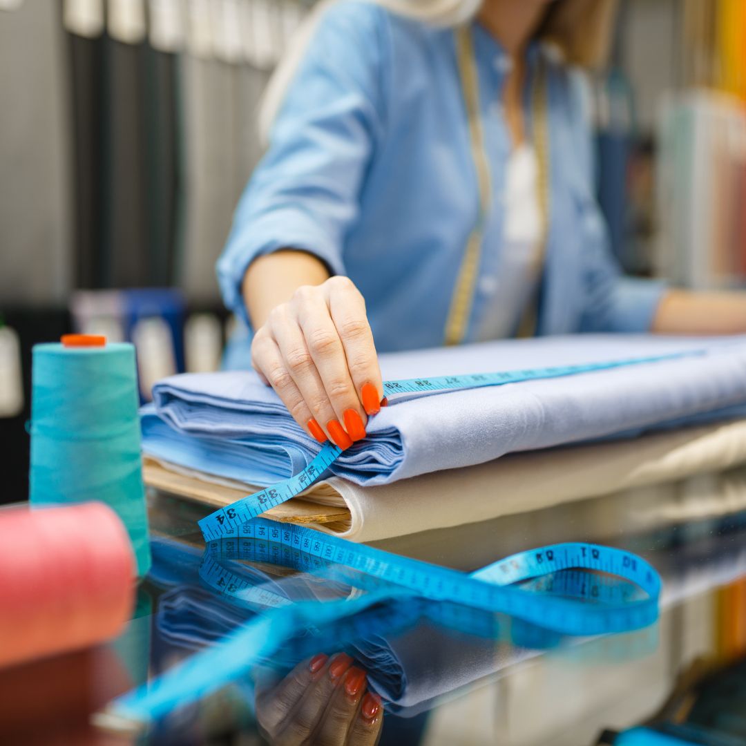 Woman measuring blue fabric. 