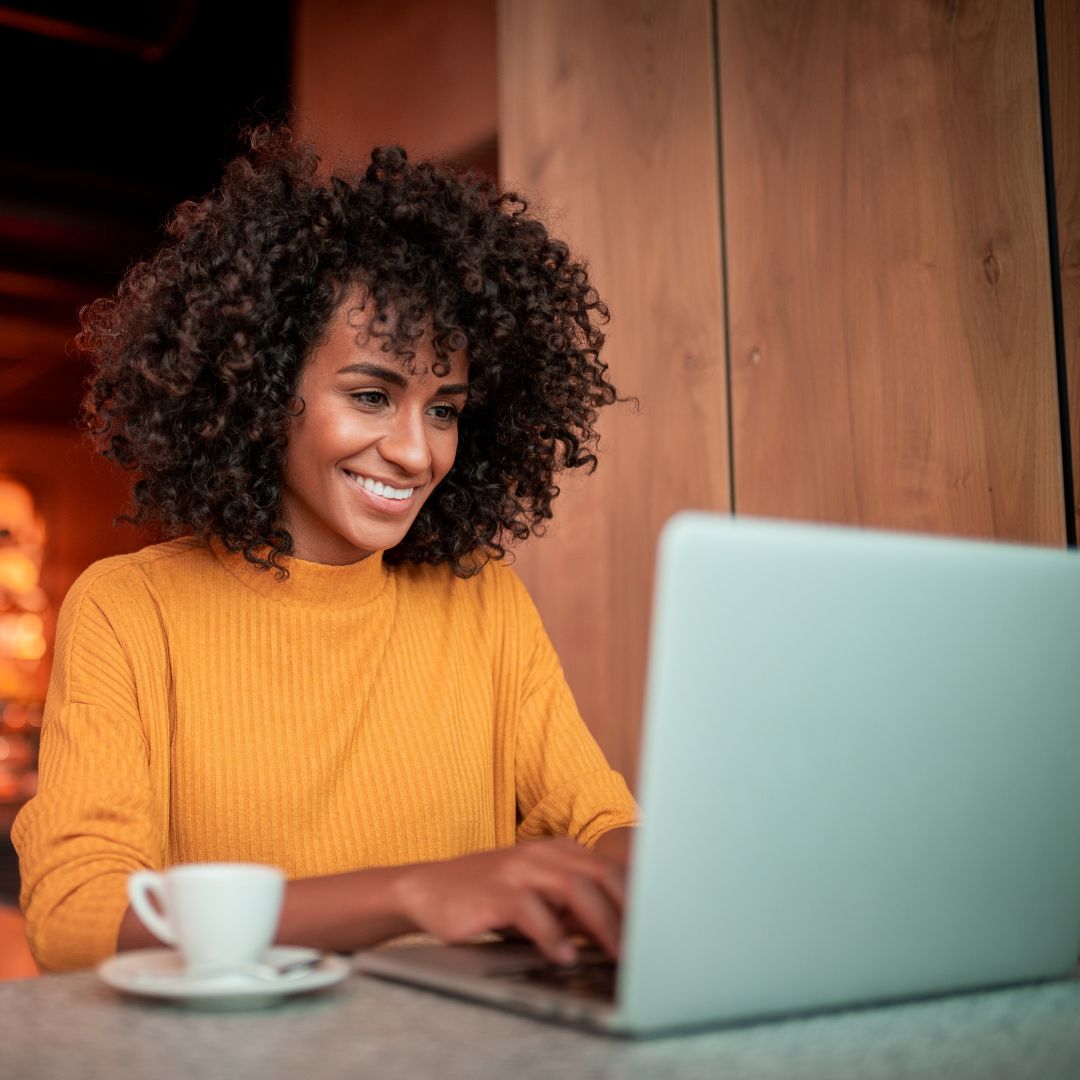 Woman smiling while typing on her laptop.